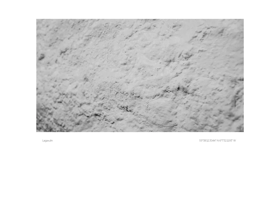 A pale, uneven monochrome surface with scattered darker marks, presented with a white print border.